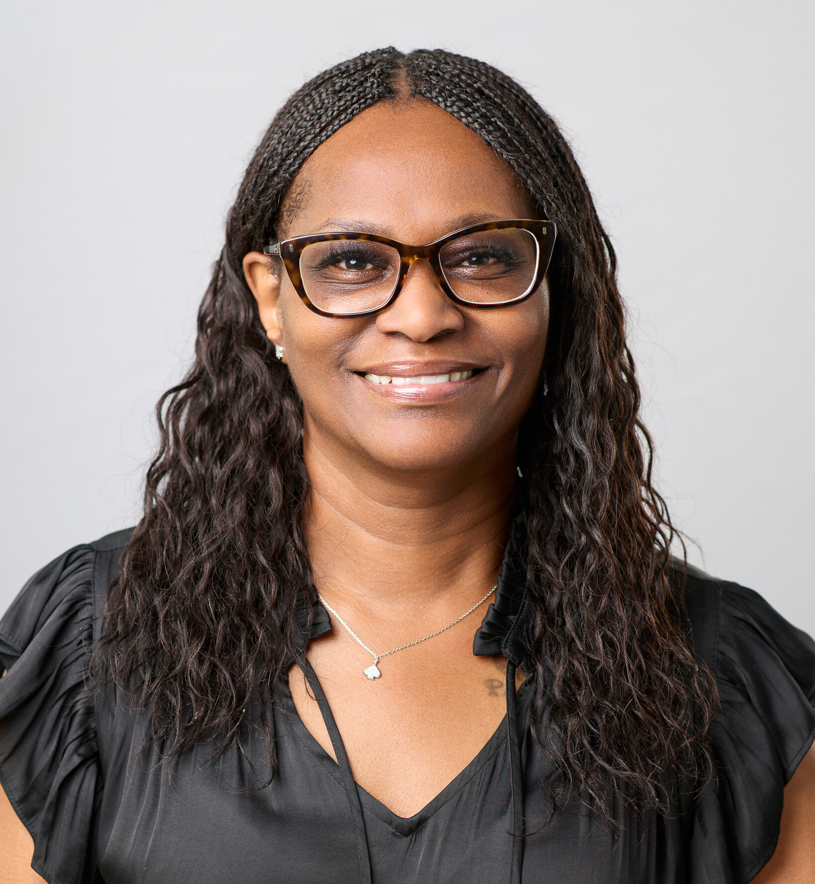 Headshot of a women in glasses wearing business professional.