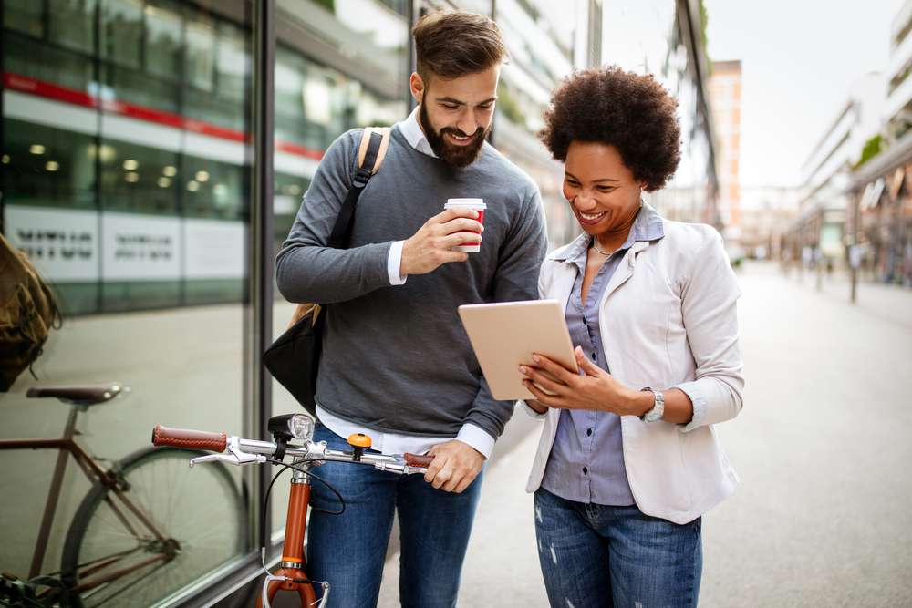 Young business workers analyzing ipad over coffee